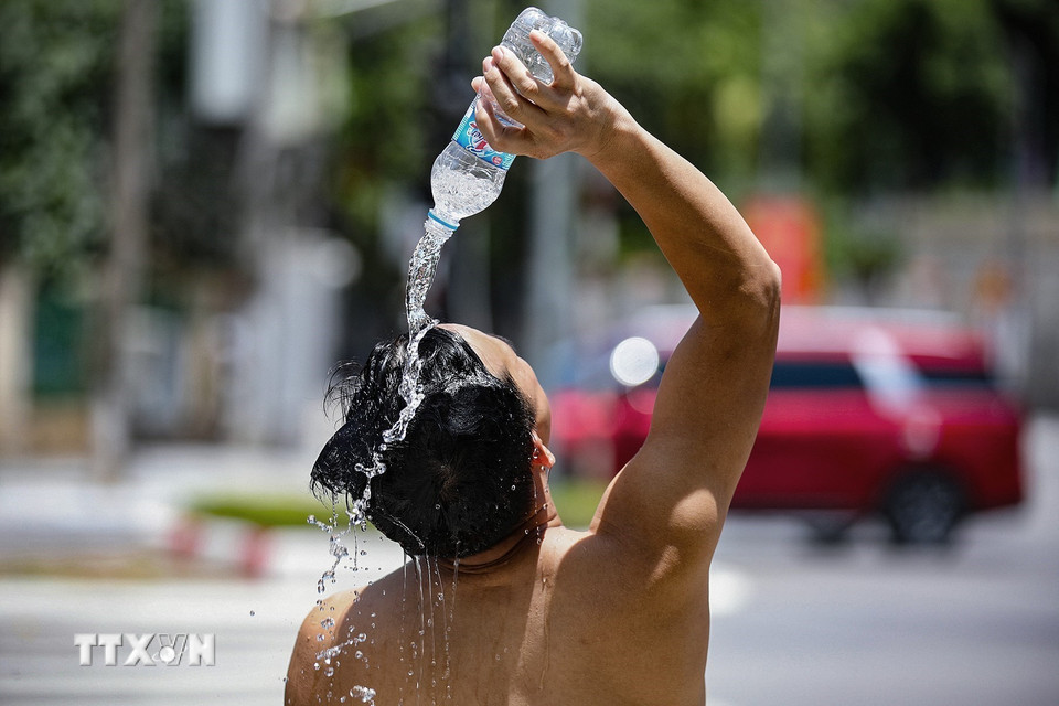 Một người lao động tự dội nước làm mát ngay trên hè phố đại lộ Thịnh Lang, thành phố Hòa Bình. (Ảnh: Trọng Đạt/TTXVN)