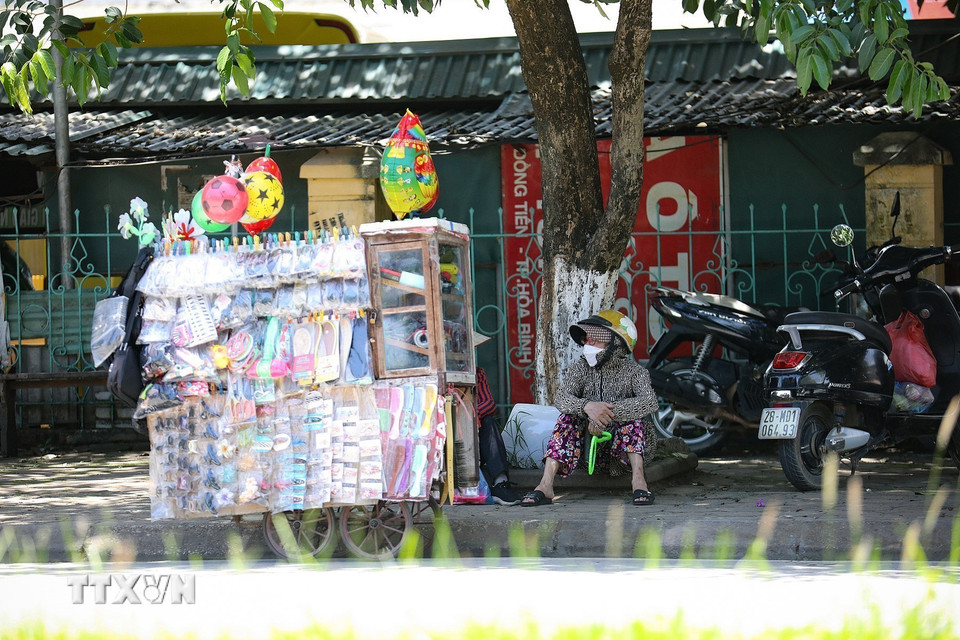 Những người phụ nữ bán hàng rong tại thành phố Hòa Bình chọn ngồi nghỉ dưới tán cây trong khi bên ngoài nhiệt độ hiện là khoảng 40 độ C.(Ảnh: Trọng Đạt/TTXVN)