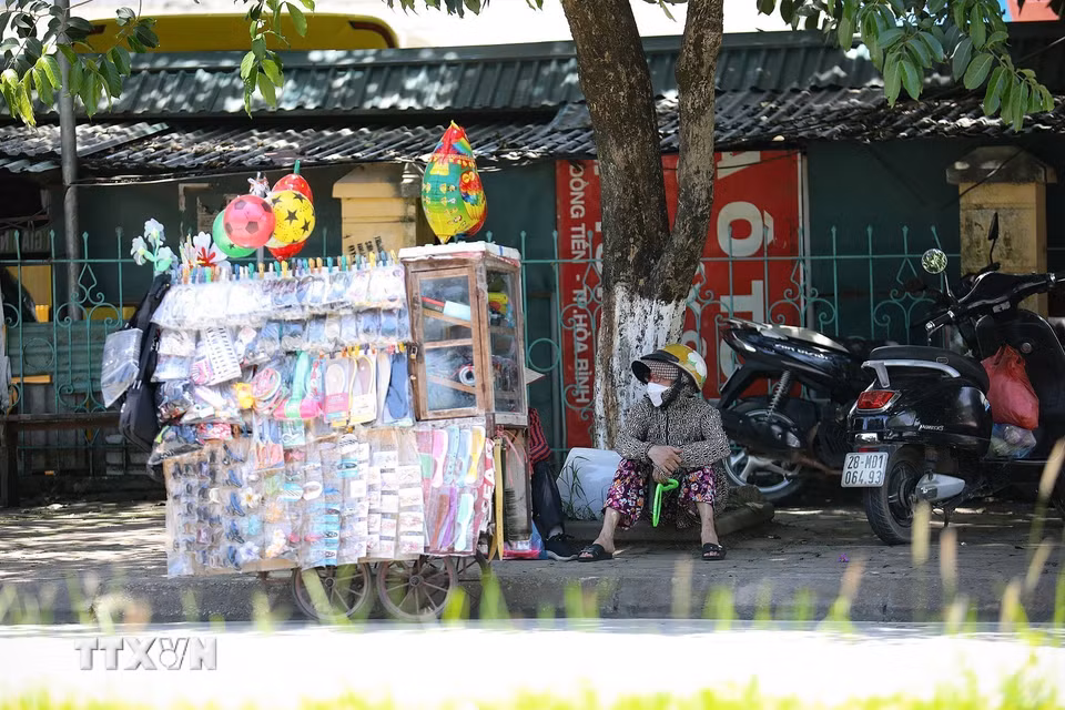 Những người phụ nữ bán hàng rong tại thành phố Hòa Bình chọn ngồi nghỉ dưới tán cây trong khi bên ngoài nhiệt độ hiện là khoảng 40 độ C.(Ảnh: Trọng Đạt/TTXVN)