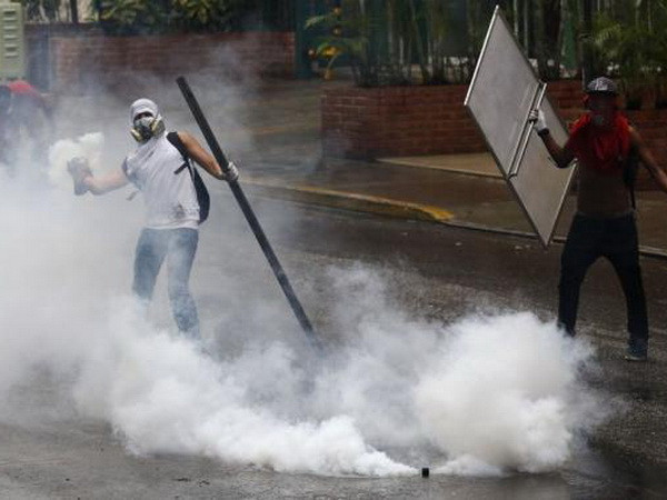 Những người biểu tình chống chính phủ ném hơi cay vào cảnh sát tại Caracas ngày 8/5. (Nguồn: Reuters) Venezuela trả tự do cho phần lớn sinh viên bị bắt giữ ảnh 1