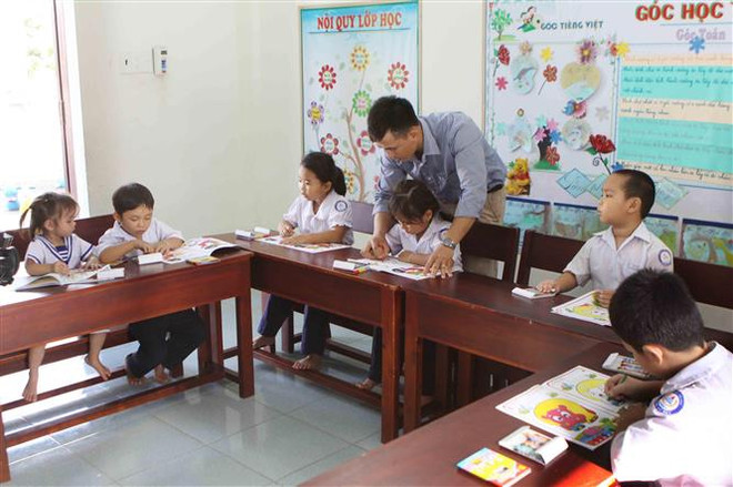 Thầy giáo Lê Xuân Quyết hướng dẫn học sinh xã đảo Song Tử Tây. (Ảnh: Dương Giang/TTXVN) Sức sống mới ở xã đảo Song Tử Tây sau 45 năm giải phóng ảnh 1