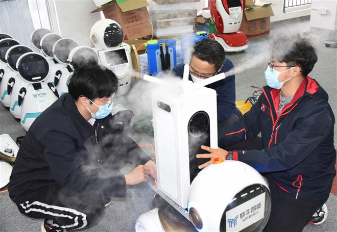 Các kỹ thuật viên kiểm tra robot khử trùng thế hệ đầu tiên tại công ty công nghệ Thanh Đảo, tỉnh Sơn Đông, Trung Quốc. (Ảnh: THX/TTXVN) Trung Quốc đẩy nhanh phát triển mạng 5G nhằm hỗ trợ chống COVID-19 ảnh 1