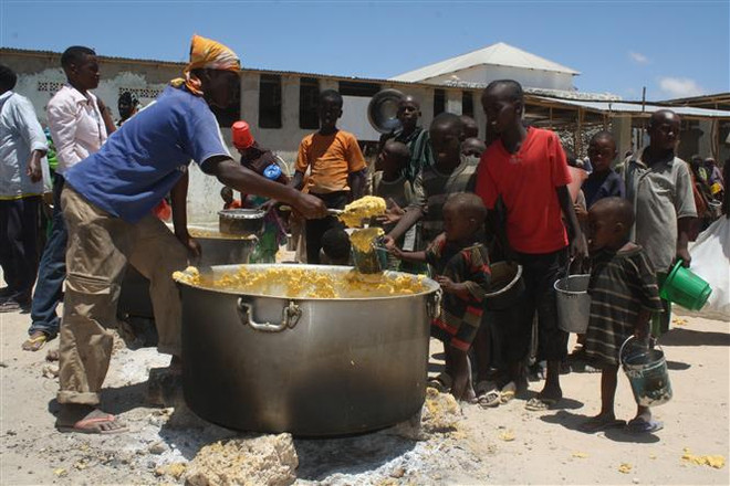 Phân phát thức ăn cứu trợ cho trẻ em tại huyện Howlwadag, Somalia. (Ảnh: AFP/TTXVN) Phân hóa giàu nghèo làm trầm trọng thêm tình trạng nghèo đói ảnh 1