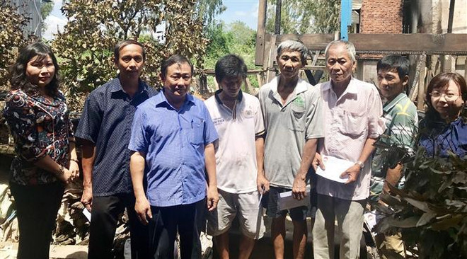 Ông Nguyễn Tiếc Hùng, Chủ tịch Ủy ban Mặt trận Tổ quốc Việt Nam tỉnh An Giang (thứ 3 trái qua), trao tiền hỗ trợ cho các hộ bị thiệt hại sau vụ hỏa hoạn. (Ảnh: Công Mạo/TTXVN) Thăm hỏi, hỗ trợ 5 gia đình có nhà bị cháy ở huyện biên giới An Phú ảnh 2