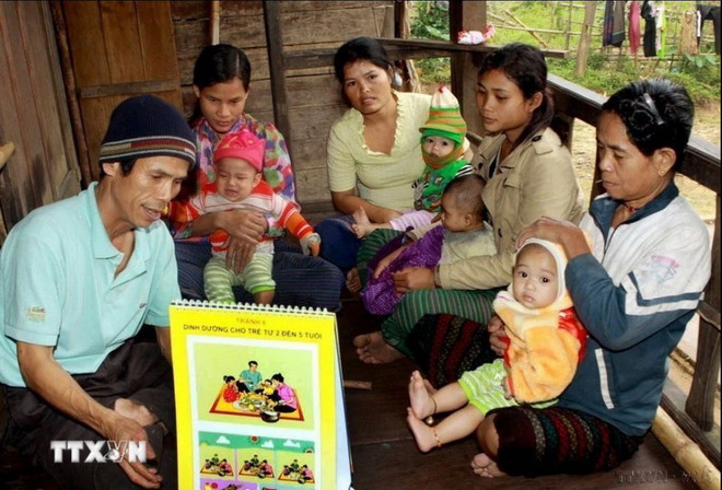 Y tế thôn bản kiểm tra tư vấn dinh dưỡng trẻ em cho đồng bào dân tộc Bru-Vân Kiều tại huyện Lệ Thủy, tỉnh Quảng Bình. (Ảnh: Dương Ngọc/TTXVN) dan so.JPG