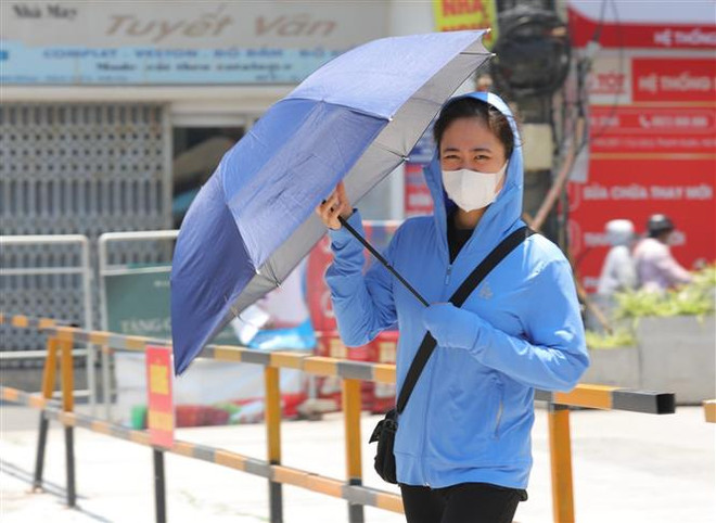 Người dân trang bị nhiều đồ chống nắng, nóng khi phải di chuyển ngoài trời. (Ảnh: Hoàng Hiếu/TTXVN) Bắc Bộ và Trung Bộ tiếp tục nắng nóng gay gắt, có nơi trên 40 độ C ảnh 1