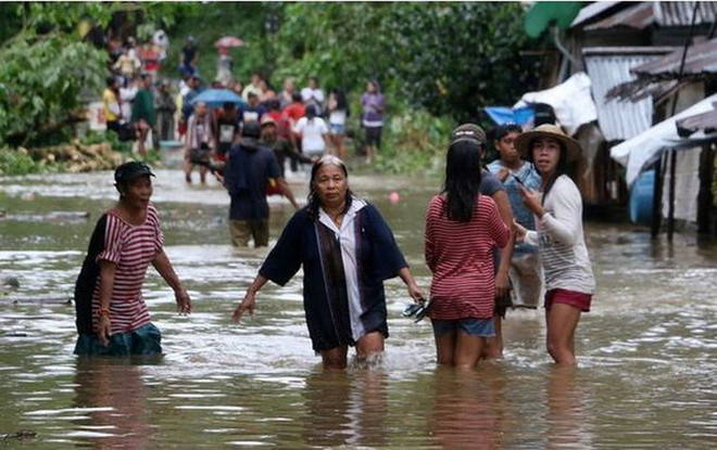 Người dân lội qua một con đường bị ngập lụt ở một ngôi làng ở Borongan, phía đông Samar, miền trung Philippines. (Nguồn: AFP) Bão Kai-Tak tàn phá Philippines, hàng chục người thiệt mạng ảnh 1