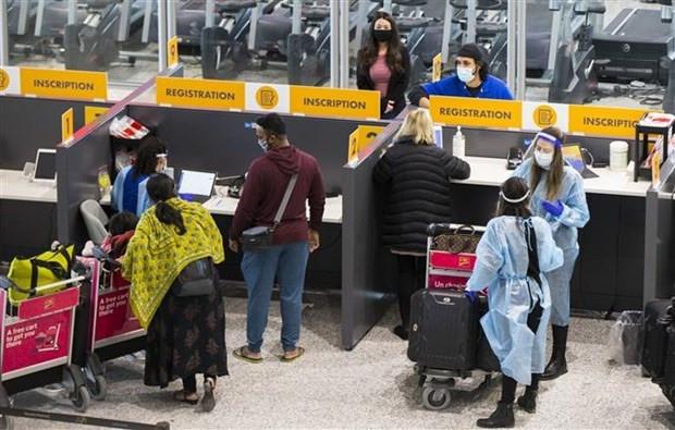Hành khách đeo khẩu trang phòng lây nhiễm COVID-19 tại sân bay quốc tế Toronto ở Mississauga, bang Ontario của Canada. (Ảnh: THX/TTXVN) Canada: Người nhập cảnh tiêm đủ 2 mũi không bắt buộc xét nghiệm PCR ảnh 1