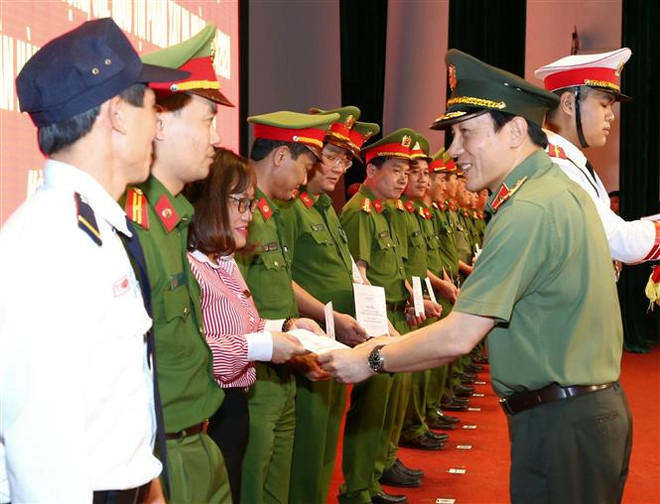Trung tướng Lương Tam Quang, Thứ trưởng Bộ Công an, trao tiền thưởng của Bộ Công an cho các cá nhân tập thể có thành tích xuất sắc. (Ảnh: Doãn Tấn/TTXVN) Khen thưởng 5 đơn vị phá chuyên án cướp tại Ngân hàng Techcombank ảnh 2