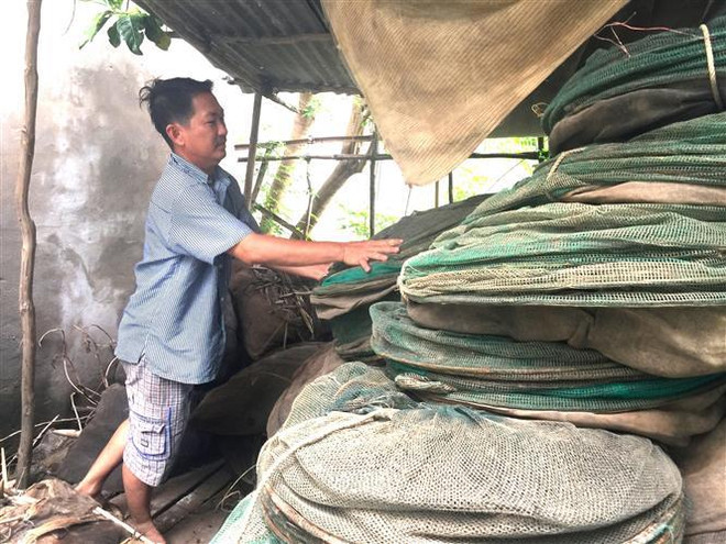 Anh Âu Văn Khải, ngụ tại ấp Tắc Trúc, xã Nhơn Hội, huyện An Phú, tỉnh An Giang, xếp gọn 2.000m lưới đánh cá để chờ bán vào mùa lũ năm sau. (Ảnh: Hồng Nhung/TTXVN) Chuyển hướng trong mùa lũ: Đồng bằng sông Cửu Long ngóng con nước lớn ảnh 1