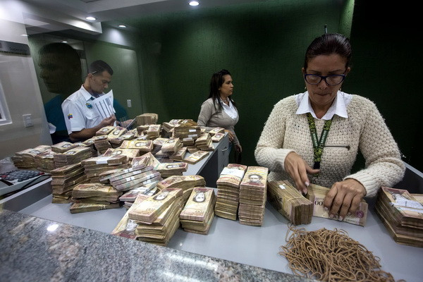 Nhân viên ngân hàng kiểm đồng 100 bolivar tại Caracas. (Nguồn: EPA/TTXVN) Venezuela cáo buộc Mỹ phá hoại công tác phát hành đồng tiền mới ảnh 1