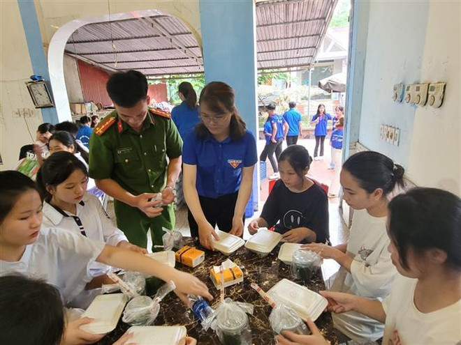 Những phần cơm nóng hổi được trao tận tay các thí sinh lúc rời phòng thi. (Ảnh: Vũ Hoàng Giang/TTXVN) Những suất cơm miễn phí cho thí sinh có hoàn cảnh khó khăn ảnh 1