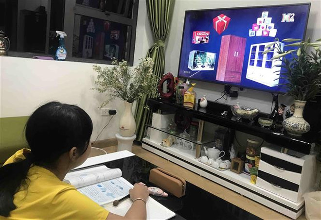 Học sinh trường Tiểu học Phương Mai (Đống Đa, Hà Nội) học qua truyền hình tại nhà. (Ảnh: TTXVN phát) Dạy tiếng Việt trên truyền hình cho học sinh lớp 1 ảnh 1