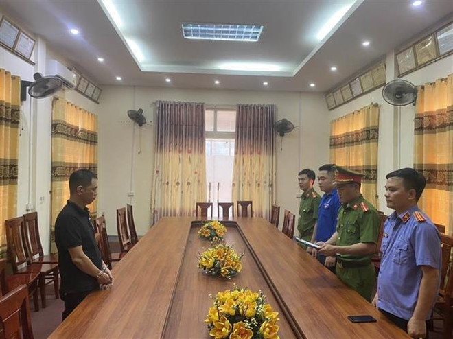 Lực lượng chức năng công bố các quyết định, lệnh bắt tạm giam đối với bị can Phạm Tiến Đạt. (Ảnh: TTXVN phát) Lừa xin cấp đất cho các đôi mới cưới, chiếm đoạt hơn 300 triệu đồng ảnh 1