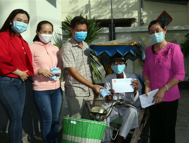 Chủ tịch Ủy ban Mặt trận Tổ quốc Việt Nam tỉnh Kiên Giang Lê Thị Vệ trao tiền hỗ trợ người bán vé số dạo trên địa bàn thành phố Rạch Giá. (Ảnh: Lê Sen/TTXVN) Quy định thực hiện chính sách hỗ trợ người dân gặp khó khăn do dịch ảnh 2