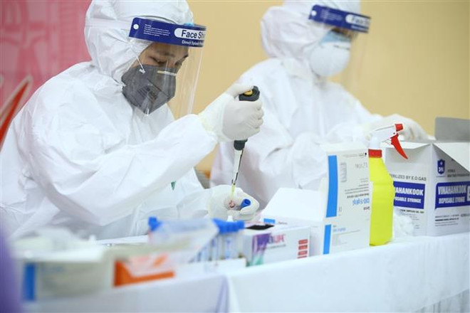 Xét nghiệm nhanh cho nhân viên, tiểu thương tại chợ đầu mối nông sản Long Biên (Ba Đình). (Ảnh: TTXVN) WHO và Anh chứng nhận bộ kít xét nghiệm COVID-19 của Việt Nam ảnh 1