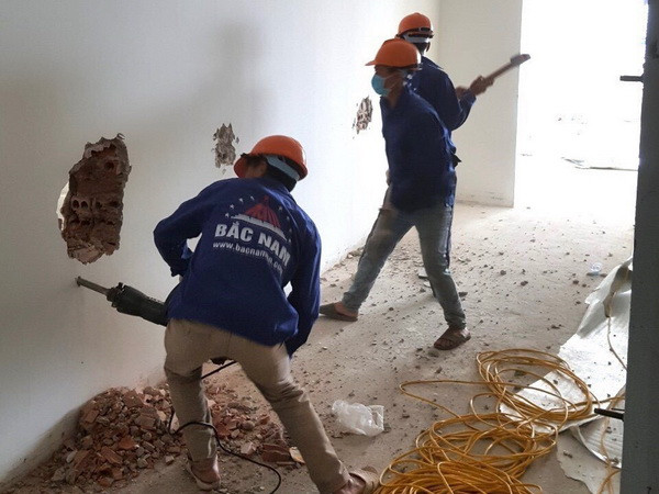 Công nhân thực hiện tháo dỡ tường phía trong tầng 18 tòa nhà 8B Lê Trực. (Ảnh: TTXVN phát) Hà Nội bắt đầu tháo dỡ tường phía trong tầng 18 tòa nhà 8B Lê Trực ảnh 1