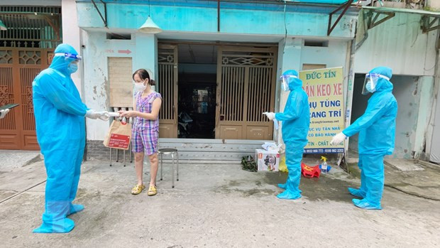 Nhân viên y tế trạm y tế lưu động phường 25, quận Bình Thạnh phát túi thuốc cho F0 điều trị tại nhà. (Ảnh: Đinh Hằng/TTXVN) Nhiều mô hình chăm sóc người mắc COVID-19 tại nhà hiệu quả ở Việt Nam ảnh 2
