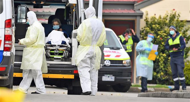 Nhân viên y tế chuyển bệnh nhân nghi mắc COVID-19 lên xe cứu thương tại bang Victoria, Australia. (Ảnh: AFP/TTXVN) Australia gia hạn lệnh phong tỏa để chống dịch tại bang Victoria ảnh 1