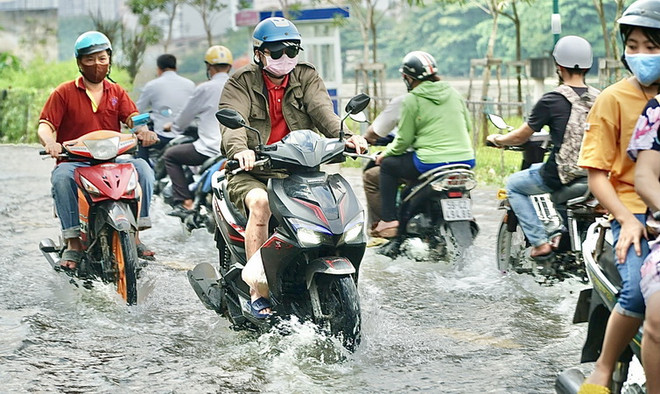 Người dân di chuyển giữa dòng nước tại đường Lê Văn Lương, huyện Nhà Bè. (Ảnh: Hồng Giang/TTXVN) TP.HCM: “Nóng ruột” chờ dự án ngăn triều cường 10.000 tỷ đồng về đích ảnh 2