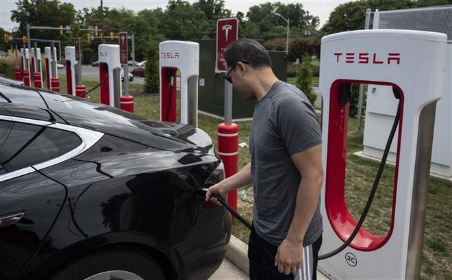 Người dân sạc điện cho ôtô tại một trạm sạc của Tesla ở Arlington, Virginia, Mỹ. (Ảnh: AFP/TTXVN) Tesla quyết định giảm tới 20% giá bán tại thị trường Mỹ và châu Âu ảnh 1