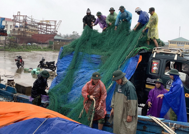 Bộ đội Biên phòng tỉnh Quảng Trị giúp ngư dân đưa lưới từ tàu cá lên bờ để phòng chống bão số 13. (Ảnh: Nguyên Lý/TTXVN) Kiểm tra công tác chuẩn bị ứng phó bão số 13 tại Quảng Bình, Quảng Trị ảnh 2