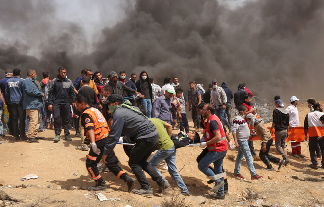 Chuyển người bị thương trong xung đột giữa người biểu tình Palestine và binh sỹ Israel phía Đông khu vực biên giới giữa Dải Gaza và Israel. (Nguồn: AFP/TTXVN) Bạo lực tiếp tục leo thang tại Gaza, thêm 4 người Palestine thiệt mạng ảnh 1
