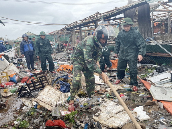 Bộ đội Biên phòng Cửa khẩu cảng Cửa Việt, tỉnh Quảng Trị hỗ trợ các hộ tiểu thương dọn dẹp, sửa chữa hàng quán bị hư hại. (Ảnh: Thanh Thủy/TTXVN) Ứng phó bão số 4-Noru: Chủ động, quyết liệt để giảm thiểu thiệt hại ảnh 2