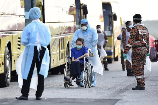Nhân viên y tế Malaysia đón các công dân nước này được sơ tán từ Vũ Hán, Trung Quốc. (Ảnh: AFP/TTXVN) Malaysia siết chặt quy định đối với tàu thuyền nước ngoài cập cảng ảnh 1