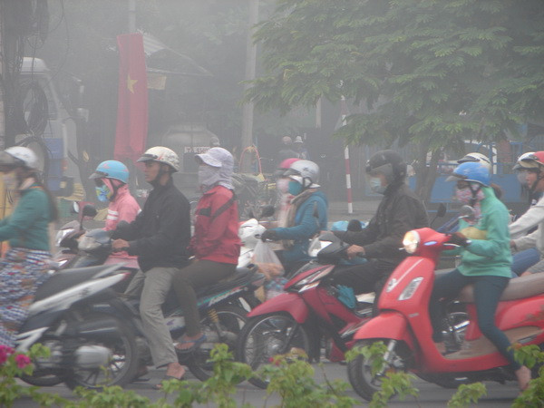 Những người đi đường phải mặc thêm áo ấm. (Ảnh: Dương Chí Tưởng/Vietnam+) Bình Dương: Hiện tượng sương mù xuất hiện dày đặc ảnh 3