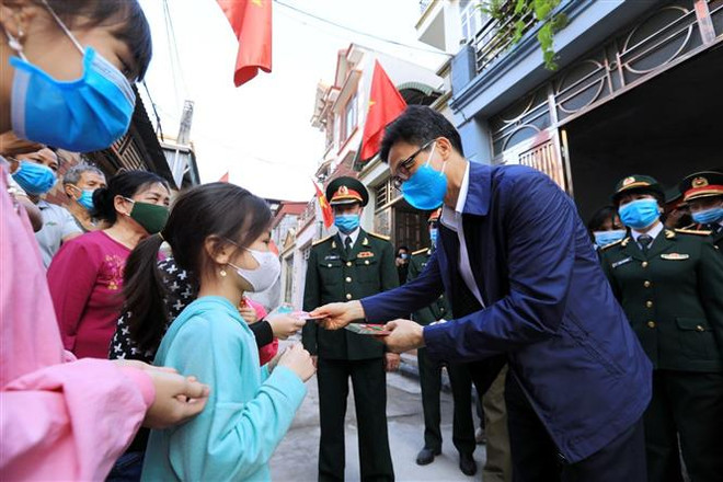 Phó Thủ tướng Vũ Đức Đam trao lì xì cho các cháu nhỏ tại tổ dân phố số 10 và 11, nhà máy Z153. (Ảnh: Thành Đạt/TTXVN) Thăm hỏi, động viên các gia đình tại khu tập thể Nhà máy Z153 ảnh 2