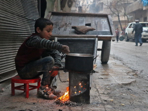 Một em bé Syria nấu ăn trên đường phố Aleppo. (Nguồn: AFP/TTXVN) Cảnh báo về nguy cơ bùng phát xung đột tại thành phố Idlib của Syria ảnh 1