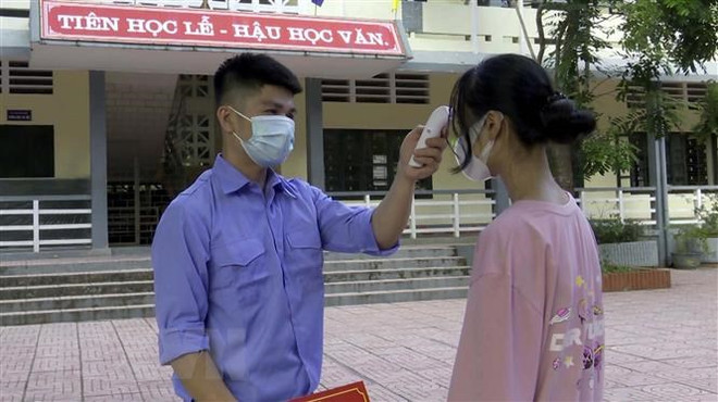 Đo thân nhiệt cho học sinh trước khi vào trường học. (Nguồn: TTXVN) Cà Mau: Sẵn sàng hỗ trợ điều trị khi có học sinh mắc COVID-19 ảnh 1