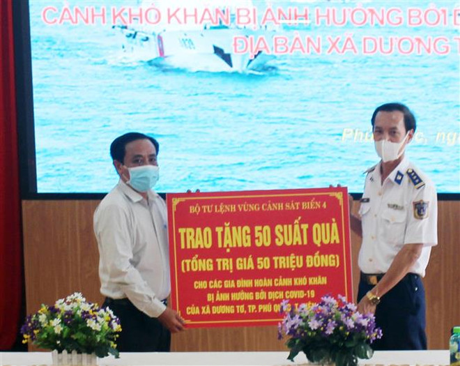 Thượng tá Lê Văn Tú, Phó Chính ủy Bộ Tư lệnh Vùng Cảnh sát biển 4, trao bảng biểu trưng tặng quà cho hộ nghèo. (Ảnh: TTXVN phát) Thắm tình quân dân vùng biên giới, biển đảo trong đại dịch COVID-19 ảnh 2