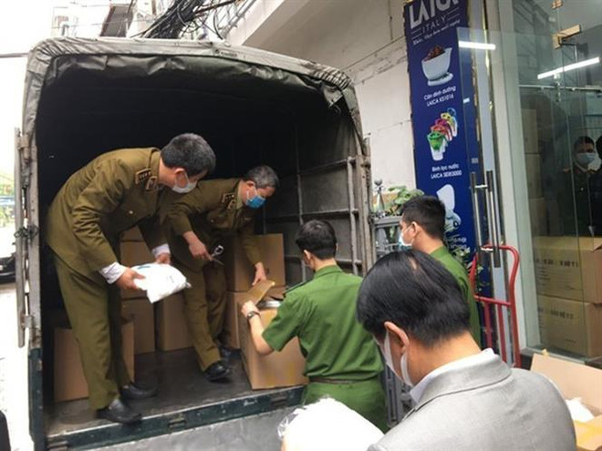 Cơ quan chức năng kiểm tra, thu giữ số hàng hóa không rõ chứng từ, nguồn gốc xuất xứ tại Công ty Đức Anh. (Ảnh: TTXVN phát) Khởi tố 3 bị can làm giả hàng nghìn bộ quần áo bảo hộ y tế ảnh 1
