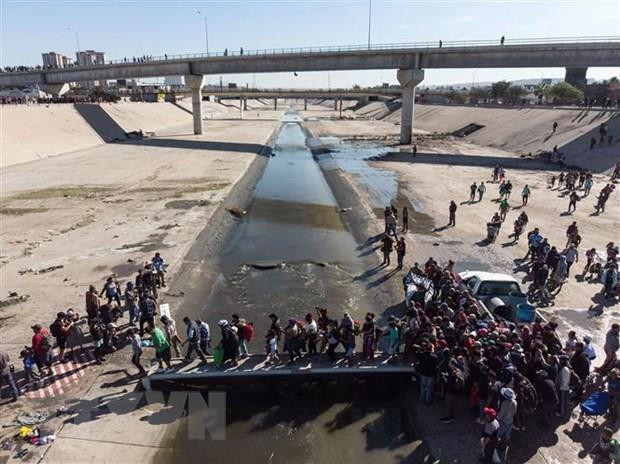 Người di cư Trung Mỹ vượt đoạn sông Tijuana để tới cửa khẩu El Chaparral, gần biên giới Mỹ-Mexico. (Ảnh: AFP/TTXVN) Ông Trump yêu cầu áp dụng tính phí với các đơn xin tị nạn ảnh 1