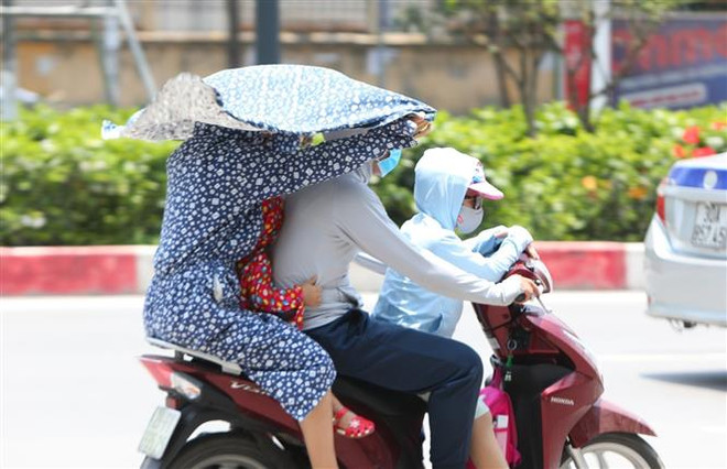 Người dân tìm mọi cách tránh nắng khi tham gia giao thông. (Ảnh: Thành Đạt/TTXVN) Trong 10 ngày tới, cả nước ngày nắng nóng, đêm có mưa và dông ảnh 1
