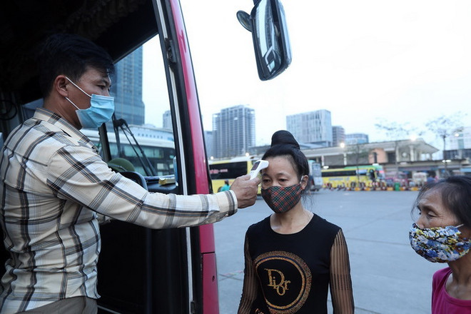 Hành khách được đo kiểm tra thân nhiệt trước khi lên xe. (Ảnh: Phan Tuấn Anh/TTXVN) Giải pháp nào tạo thuận lợi cho vận tải liên tỉnh thời dịch COVID-19? ảnh 1