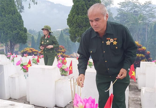 Ông Mai Đức Ngời, cựu chiến binh mặt trận Vị Xuyên, thắp hương cho đồng đội tại Nghĩa trang Liệt sỹ quốc gia Vị Xuyên. (Ảnh: Nguyễn Chiến/TTXVN) An táng hài cốt liệt sỹ tại Nghĩa trang Liệt sỹ Quốc gia Vị Xuyên ảnh 1