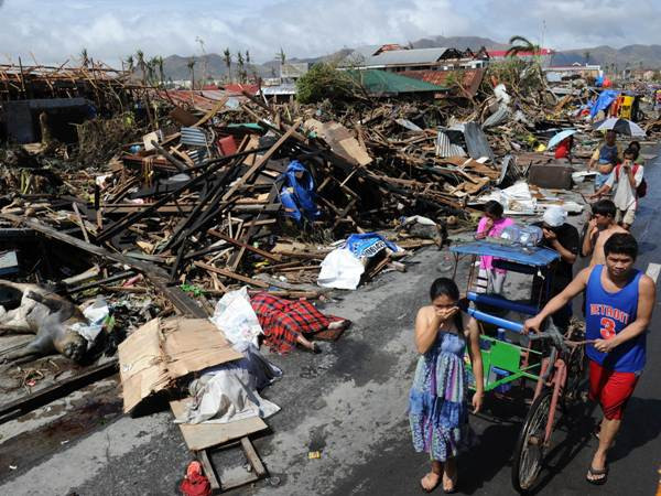 Người dân đi bên đống đổ nát sau bão Haiyan ở thành phố Tacloban, miền trung Philippines hôm 10/11. (Ảnh: AFP/TTXVN) LHQ xác nhận 4.460 người ở Philippines chết vì bão Haiyan ảnh 1