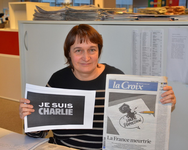 Bà Nathalie Lacube cầm trên tay khẩu hiệu "Chúng tôi là tòa soạn Charlie" và tờ báo La Croix số ra ngày 8/1 với bức tranh căng to trên trang nhất cho thấy tự do ngôn luận bị đe dọa. (Ảnh: Bích Hà/Vietnam+) Cuộc chiến không bình đẳng giữa người cầm bút và kẻ có súng ảnh 1