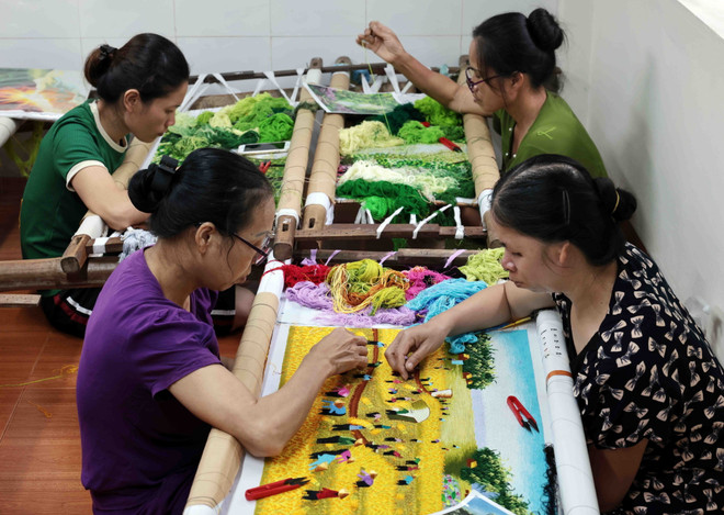 Các nghệ nhân tại cơ sở thêu Đức Tôn ở phố Tía, xã Thắng Lợi cần mẫn với sản phẩm tranh thêu phong cảnh. (Ảnh: Trần Việt/TTXVN) ttxvn_nghe theu5.jpg