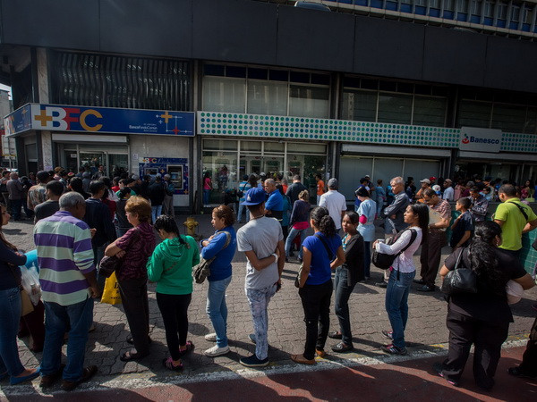 Người dân Venezuela xếp hàng chờ giao dịch bên ngoài Ngân hàng Trung ương ở Caracas. (Nguồn: EPA/TTXVN) OAS triệu tập phiên họp bất thường về tình hình Venezuela ảnh 1