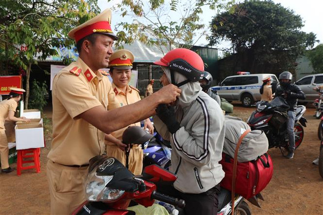 Cảnh sát giao thông Đắk Nông tuyên truyền pháp luật về trật tự an toàn giao thông, đồng thời đổi mũ bảo hiểm đạt chuẩn cho người dân. (Ảnh: TTXVN phát) Phó Thủ tướng Trương Hòa Bình gửi Thông điệp về an toàn giao thông ảnh 1