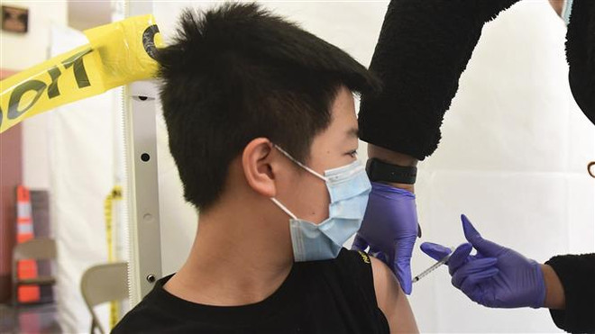 Nhân viên y tế tiêm vaccine phòng COVID-19 cho trẻ em tại Los Angeles, California, Mỹ. (Ảnh: AFP/TTXVN) Nhiều bang ở Mỹ áp dụng quy định bắt buộc trình chứng nhận tiêm chủng ảnh 1