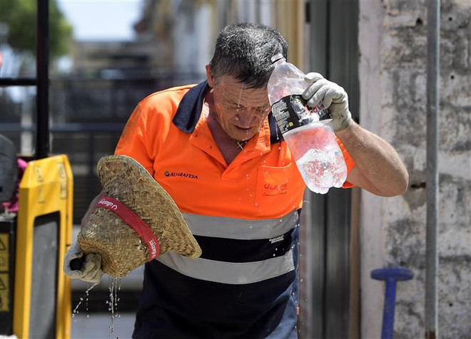 Công nhân làm mát dưới trời nắng nóng ở Sevilla, Tây Ban Nha. (Ảnh: AFP/TTXVN) Nắng nóng cực đoan còn kéo dài đến hết tháng 8 trên nhiều khu vực ảnh 1