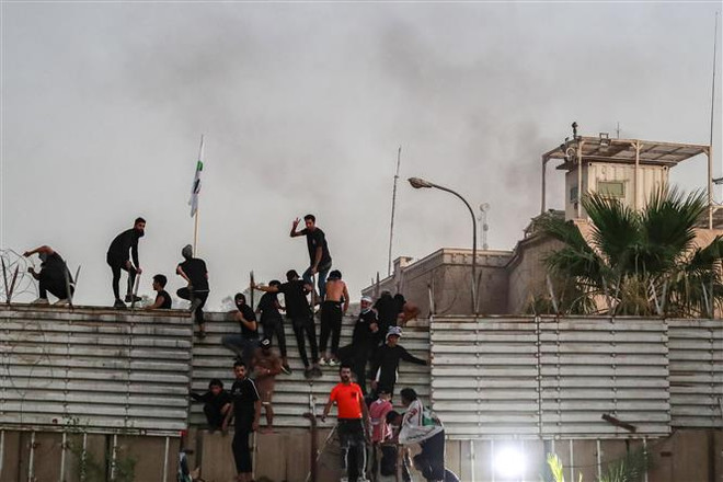 Người biểu tình trèo qua hàng rào bên ngoài Đại sứ quán Thụy Điển tại thủ đô Baghdad, Iraq. (Ảnh: AFP/TTXVN) Thụy Điển tạm di dời nhân viên Đại sứ quán tại Iraq do lo ngại an ninh ảnh 1