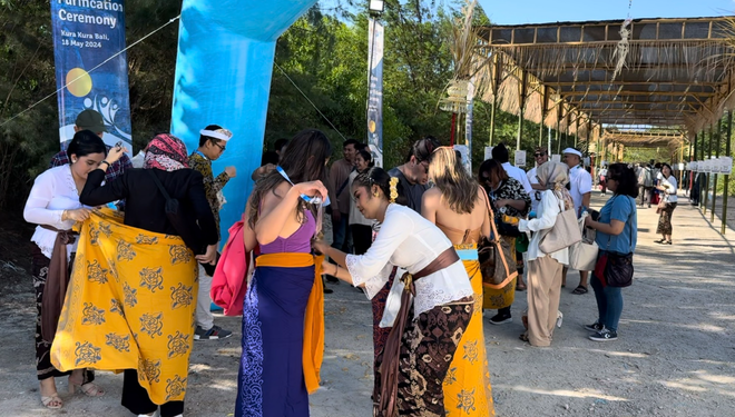 Khách tham dự được giúp quấn sarong truyền thống của người Bali. (Ảnh: Đỗ Quyên) Screenshot_1.png