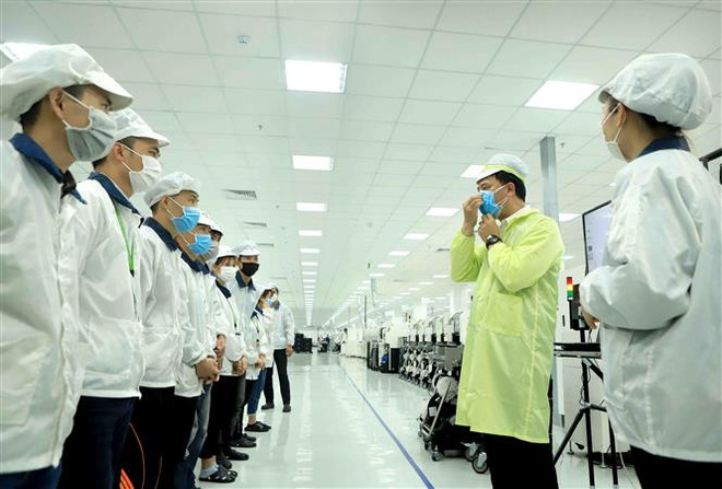Công ty TNHH Compal Việt Nam trong khu công nghiệp Bá Thiện 1 (huyện Bình Xuyên) hướng dẫn cho công nhân đeo khẩu trang đúng cách để phòng dịch COVID-19. (Ảnh: Hoàng Hùng/TTXVN) Vĩnh Phúc tăng cường quản lý chất thải phòng chống dịch COVID-19 ảnh 1
