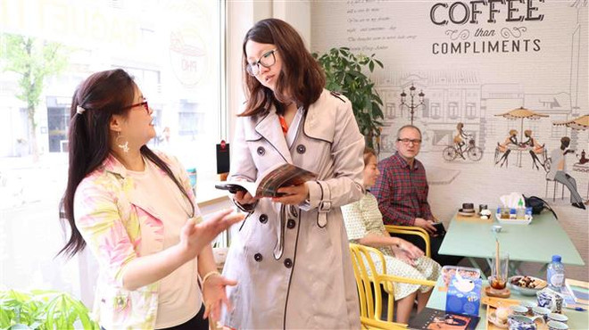 Chị Li Li Chong, người Malaysia (phải), trao đổi với chị Kiều Bích Hương, phụ trách Kênh Việt Happiness Station về dự án “Tủ sách Việt trong nhà hàng Việt ở nước ngoài.” (Ảnh: Hương Giang/TTXVN) Tủ sách Việt trong nhà hàng Việt - Đưa sách Việt tới gần độc giả ảnh 2